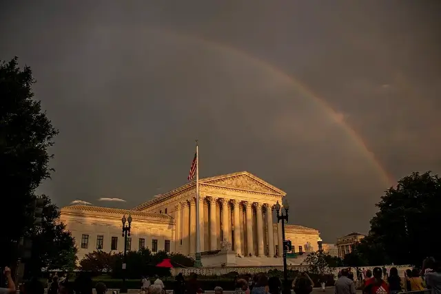The U.S. Supreme Court building at dusk with a rainbow overhead